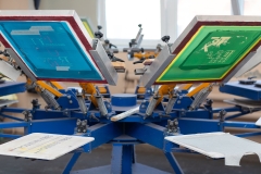 Serigraphy silk screen print process at clothes factory. Frame, squeegee and carousel